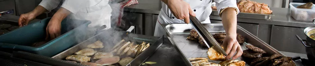 Griffith Chefs working in a kitchen to grill burgers and chicken breasts.