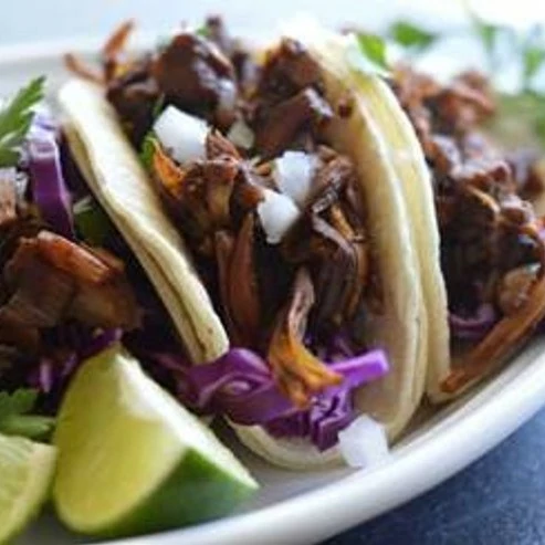Jackfruit barbacoa tacos servied in a corn tortilla and topped with salsa verde.