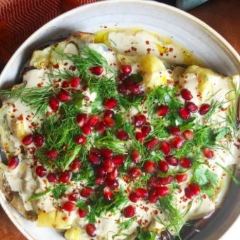 Whole roasted eggplant topped with pomegranate seeds provides functional wellness 