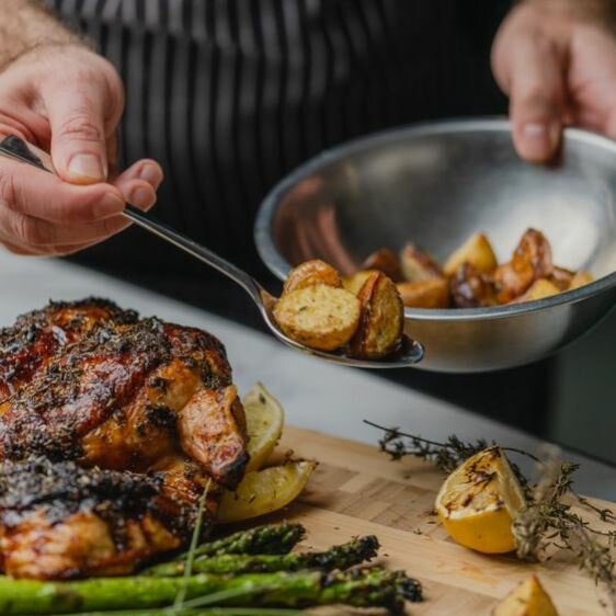 Griffith chef demonstrating culinary expertise with a roasted chicken and potato dish.
