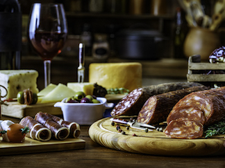 Tapas of cheese, cured ham, salami, wine and chorizo on a rustic wooden table