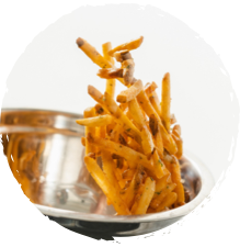 Fries being tossed in a Griffith Foods Flavour Glaze finishing oil to help them maintain crispness during delivery.