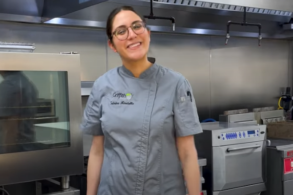 Chef Sabrina smiling at the camera in the Griffith Foods Kitchen, ready to make pork carnitas tacos.