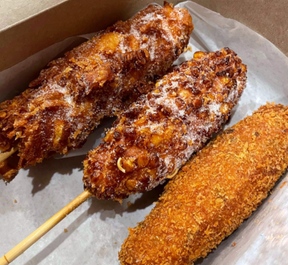 Three fried corn dogs in a to-go holder