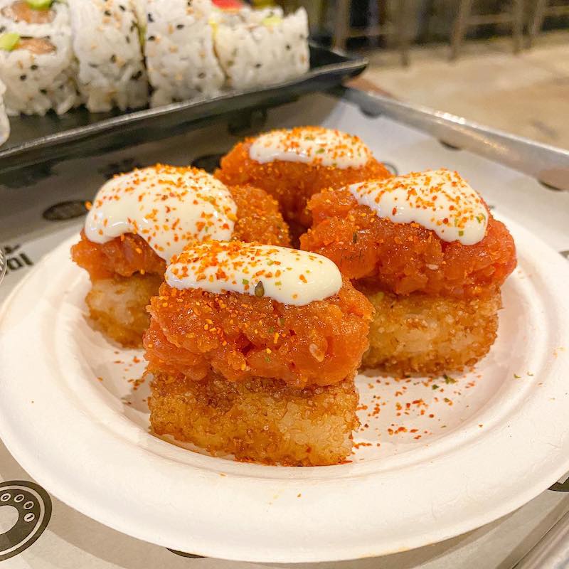 Crispy rice topped with raw tuna, a dallop of white sauce, and seasoning.