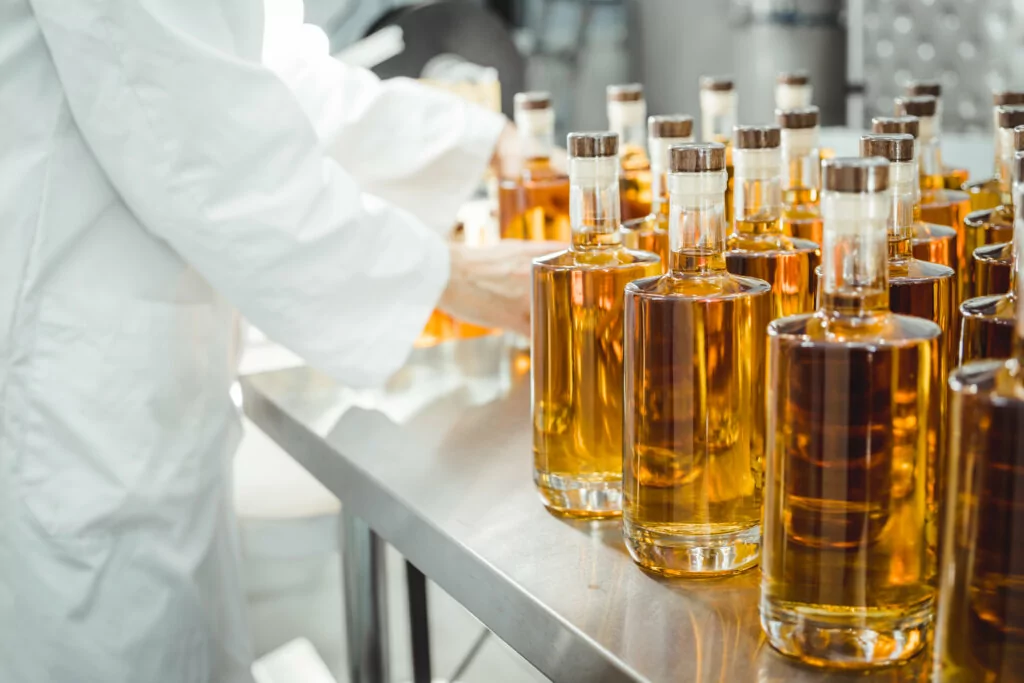 Person in lab coat analyzing bottles of pure alcohol. stock photo