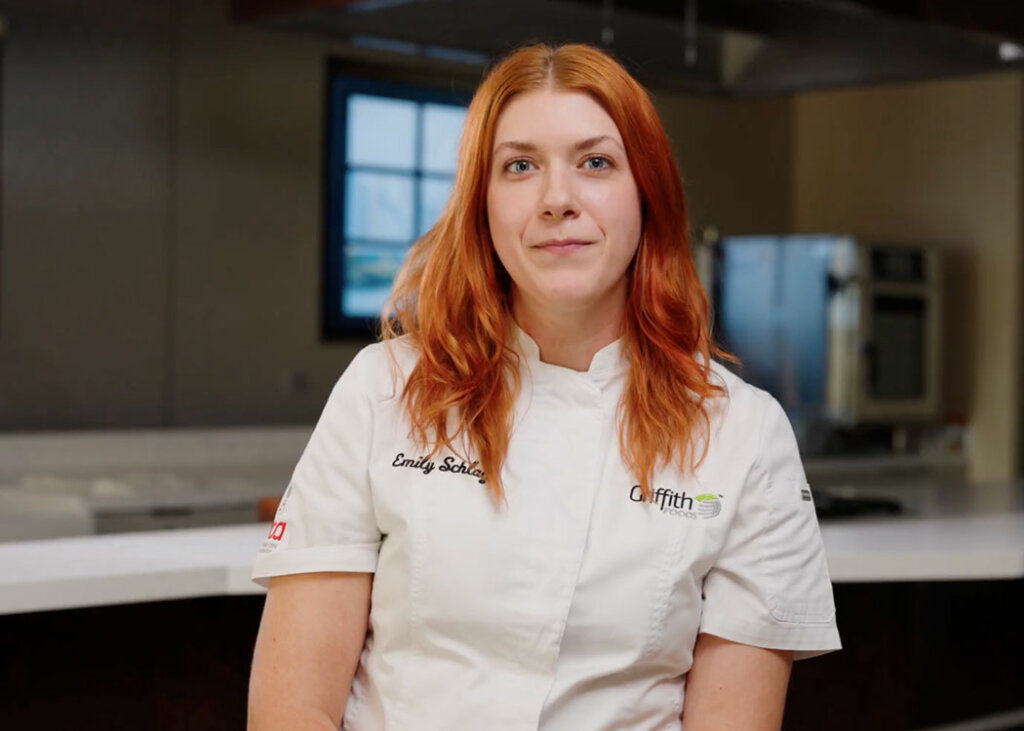 A red haired Griffith Foods chef with the name tag "Emily" on her shirt